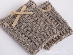 two crocheted square coasters with bows on them, one in grey and the other in beige