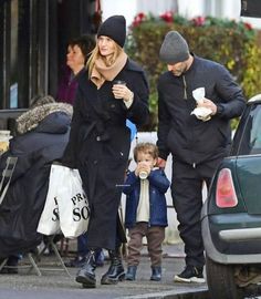 a man, woman and child are walking down the street with food in their hands