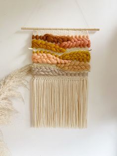 a wall hanging with several different colors of yarn on it and a piece of wood in the middle