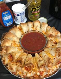 a pizza pie with sauce and condiments on the side