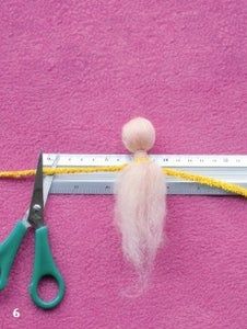 a pair of scissors, needle and thread on a pink surface next to a ruler