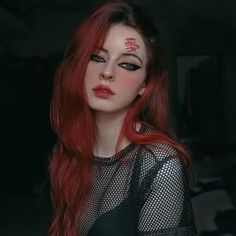 a woman with long red hair and makeup has the word love painted on her face