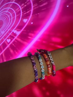 three bracelets with words written on them in front of a pink background and neon lights