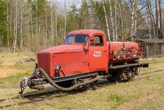 an old red truck is parked on the tracks