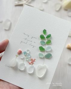 a hand holding a card with sea glass flowers on it and the words, may you have a great day