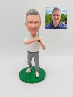 a bobble head with a man holding a baseball bat on top of a green base