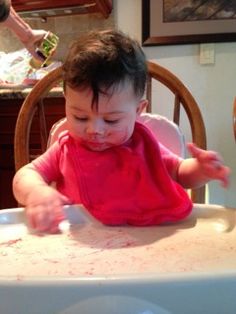 a baby sitting in a high chair with food all over it