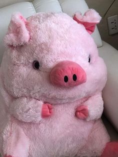 a pink stuffed pig sitting on top of a white chair