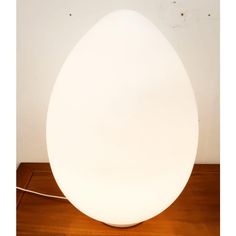 an egg shaped lamp sitting on top of a wooden table