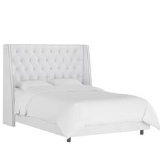 a white bed with tufted headboard and pillows on the top of it, against a white background