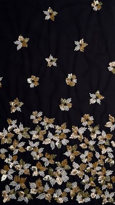 a black background with gold and silver sequins in the shape of flowers on it