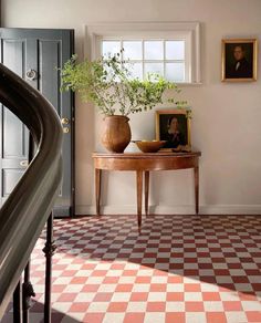 a room with a checkered floor and potted plant on the table next to it