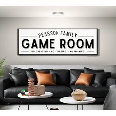 a living room with black leather furniture and a large game room sign on the wall