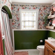 a bathroom with floral wallpaper and rugs on the floor, along with green walls