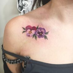 a woman's shoulder with three pansies tattoo on her left shoulder and chest