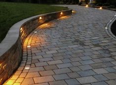 a brick walkway with lights on it and grass in the backround behind it