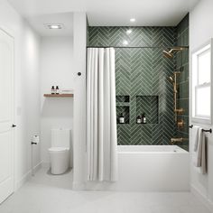 a bathroom with green and white tiles on the walls, shower curtain, toilet and tub