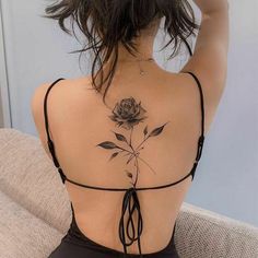 the back of a woman's body with a rose tattoo on her left shoulder