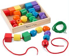 an assortment of wooden beads and cords in a box with red string on the side