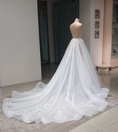 a white wedding dress on display in a room with mannequins behind it