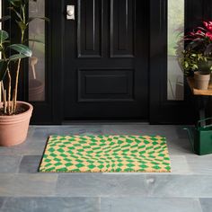 a green and yellow rug sitting on top of a floor next to a potted plant