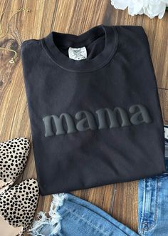 mama Tshirt 3D Puff Print Comfort Colors: Black Hey Mama! Show off your supermom status in our fabulous 3D Puff Print Mama T-Shirt! This cute and trendy tee features a bold "MAMA" design in eye-catching 3D puff print, giving it that extra pop of fun and flair. Product Details: Material: Cozy up in high-quality Comfort Colors fabric that's soft, durable, and oh-so-comfy. Color: Sleek black, perfect for mixing and matching with your favorite outfits. Design: Adorable "MAMA" text in raised 3D puff Vinyl Tee Shirt Ideas, Mama Shirt Ideas Vinyl, Black Crew Neck Tops For Mother's Day, Relaxed Fit Black Top For Mother's Day, Puff Print Design, Puff Vinyl Shirt Ideas, Puff Print Tshirt, Tshirt Design Ideas Trendy, Trendy Tshirt Designs