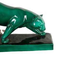 a green statue of a cat on a black base