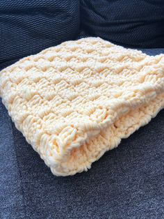 a white crocheted blanket sitting on top of a couch