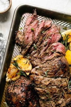 steak with lemons and rosemary garnish in a roasting pan