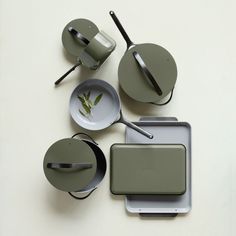 an assortment of kitchen utensils and pans on top of a white table