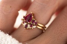 a woman's hand with a gold ring and two red stones on the band