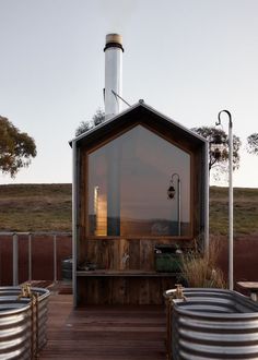 a wooden deck with metal tubs on it and a building in the back ground