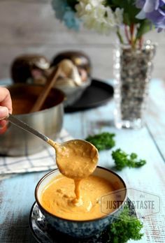 a spoon full of peanut butter being lifted from a bowl with parsley on the side