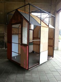 a small house made out of wood and glass in an empty room with tile flooring