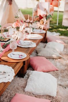 a table set up with plates and napkins for an outdoor dinner party in the grass