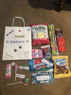 an assortment of candy and snacks laid out on the floor next to a shopping bag