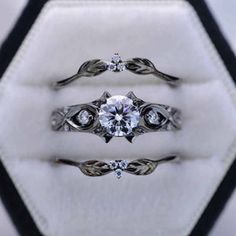 three wedding rings sitting on top of each other in a white box with black trim