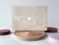 an apple computer sitting on top of a wooden stand next to other round objects in front of a white wall