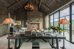 a living room filled with lots of furniture next to large windows and a stone fireplace