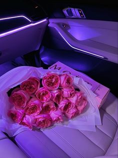 a bunch of pink roses sitting on top of a bag in the back seat of a car