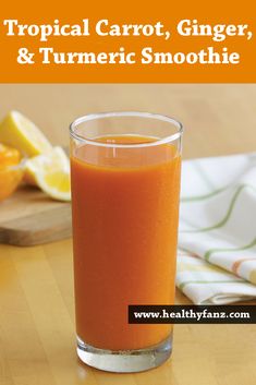 an orange smoothie in a glass on a table with the title tropical carrot, ginger and turmic smoothie