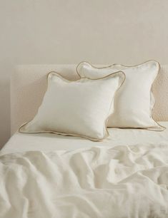 two white pillows sitting on top of a bed