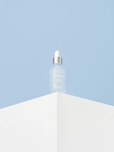 a bottle of water sitting on top of a white wall with a blue sky in the background