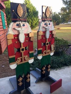 two wooden nutcrackers standing next to each other in front of a house