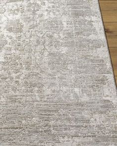 an area rug with white and gray colors on the floor in front of a wooden floor