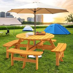 picnic tables and umbrellas are set up on the grass in front of a city skyline