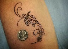 a close up of a person's arm with a tattoo on it and a coin