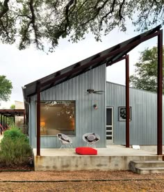 two chairs are sitting on the concrete steps in front of a metal building with an awning