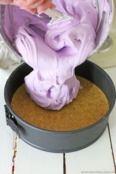 someone is mixing purple icing in a pan