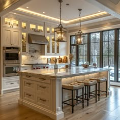 a large kitchen with an island and lots of stools in front of the window